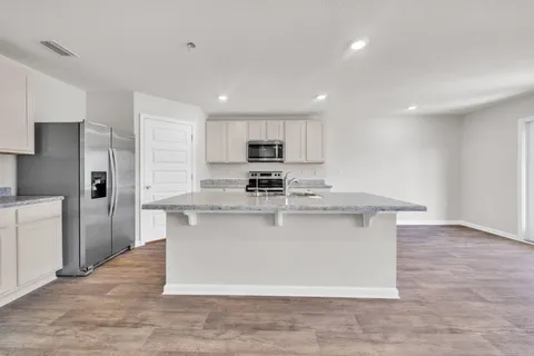 a view of kitchen with stainless steel appliances granite countertop a stove a sink and a refrigerator