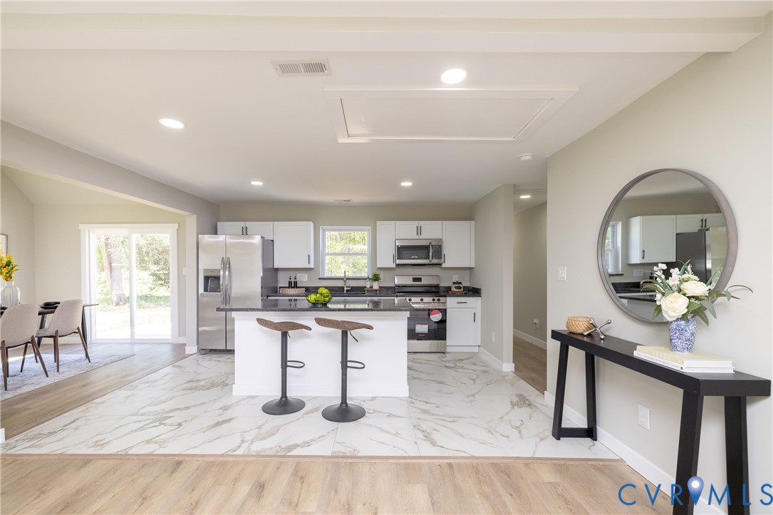 7272 Willson Road Henrico, VA 23231 - Photo 13 of 47 a kitchen with stainless steel appliances kitchen island granite countertop a stove top oven a sink a dining table and chairs