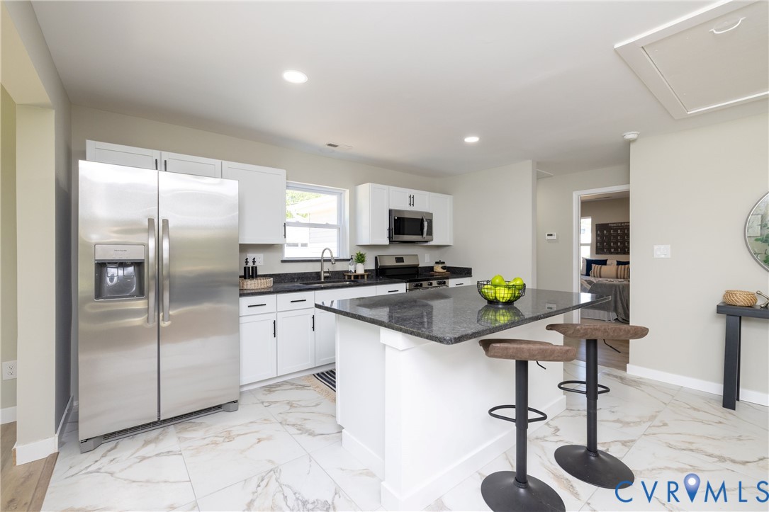 7272 Willson Road Henrico, VA 23231 - Photo 14 of 47 a kitchen with stainless steel appliances kitchen island granite countertop a refrigerator a stove a sink a dining table and chairs