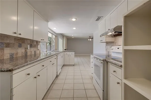 a large white kitchen with granite countertop a sink