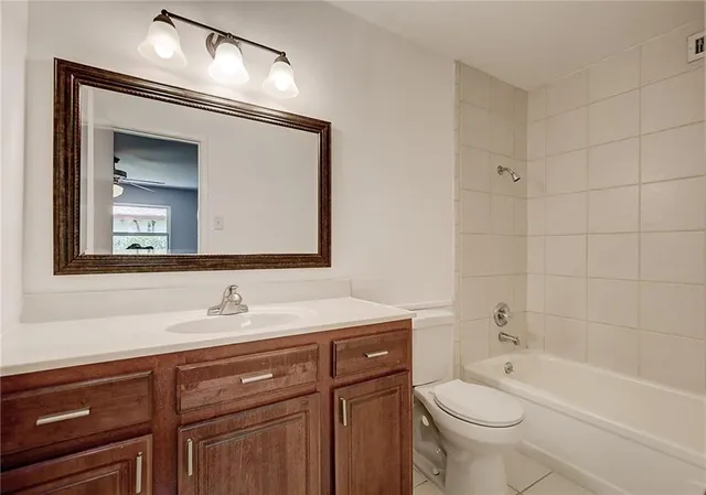 a bathroom with a toilet a sink a tub and a mirror