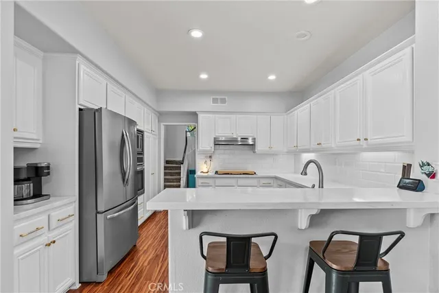 a kitchen with stainless steel appliances granite countertop a table chairs sink refrigerator and cabinets