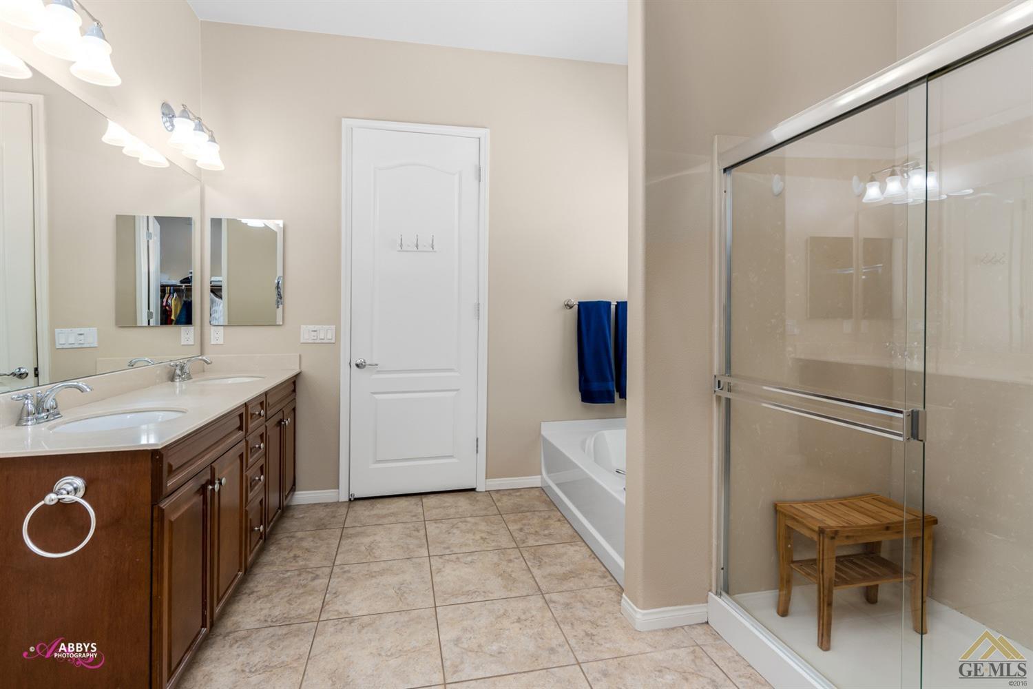 Undisclosed Address Bakersfield, CA 93306 - Photo 23 of 48 a spacious bathroom with a double vanity sink a mirror and a bathtub