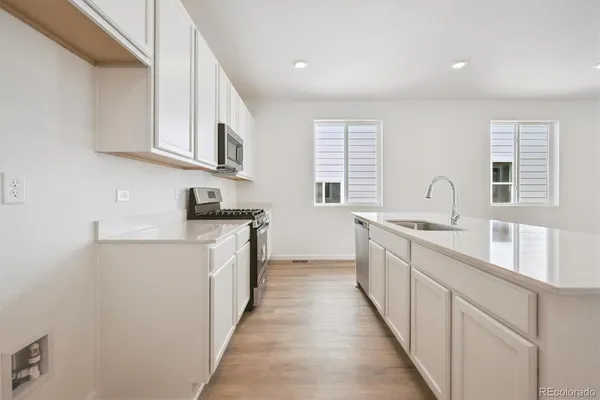 a kitchen with stainless steel appliances granite countertop a sink and dishwasher a stove top oven with wooden floor