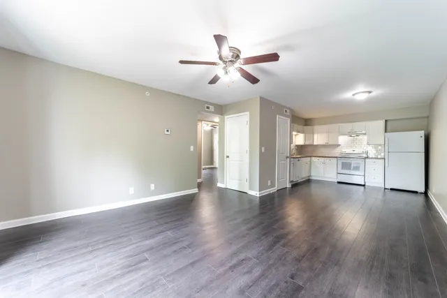 a view of an empty room with wooden floor and a ceiling fan