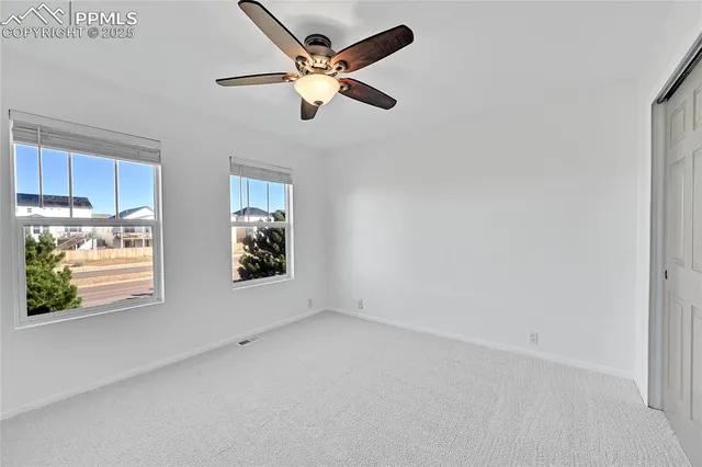 an empty room with a window and a ceiling fan