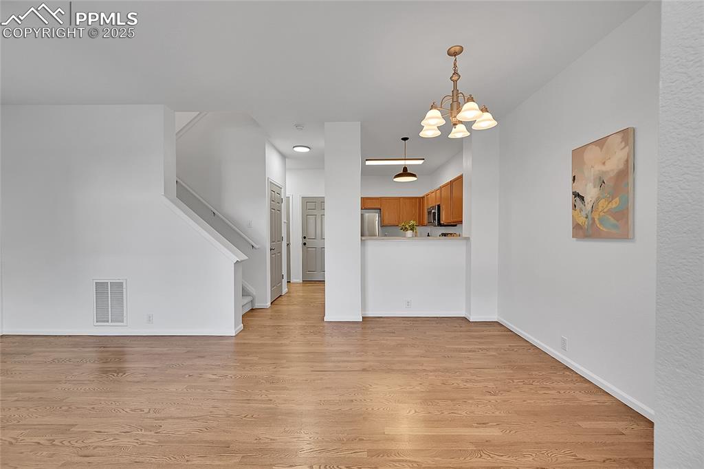 6232 Sierra Grande Point Colorado Springs, CO 80923 - Photo 7 of 31 a view of a hallway with wooden floor and a kitchen