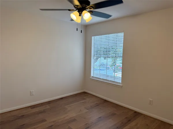 a view of an empty room with window and chandelier fan
