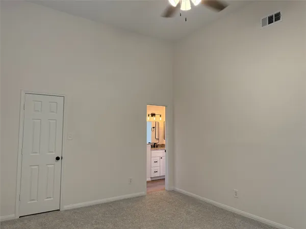 a view of an empty room and chandelier fan
