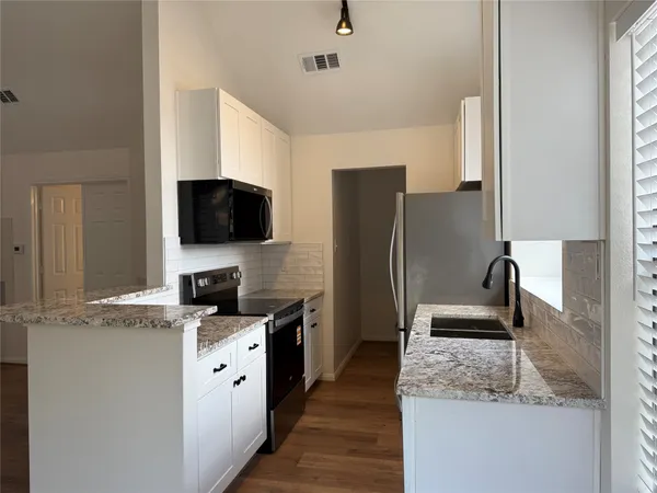 a kitchen with granite countertop a refrigerator and a sink