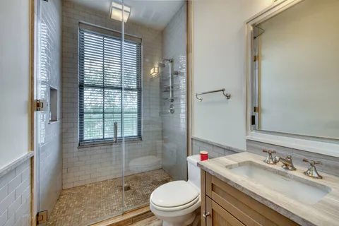 a bathroom with a granite countertop sink toilet a mirror and shower