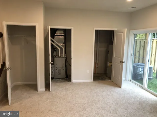 a view of an empty room with closet and a bathroom