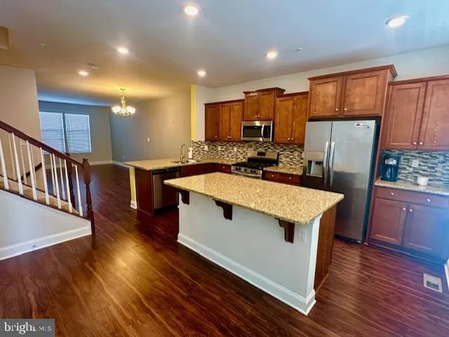 a kitchen with stainless steel appliances a kitchen island hardwood floor sink stove wooden cabinets and entryway