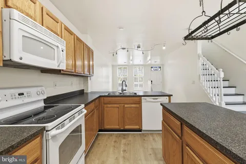 a kitchen with granite countertop a sink a stove and cabinets