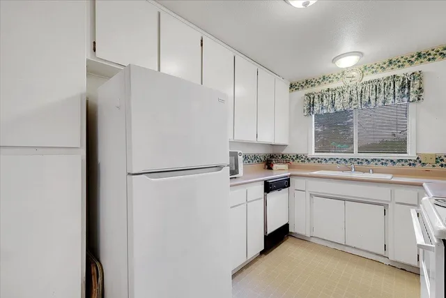a kitchen with a sink a refrigerator and cabinets