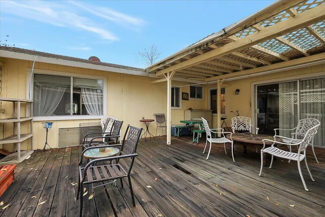 a view of a patio with table and chairs with wooden floor and fence