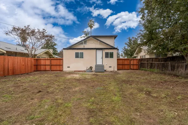 a view of backyard of house with wooden fence