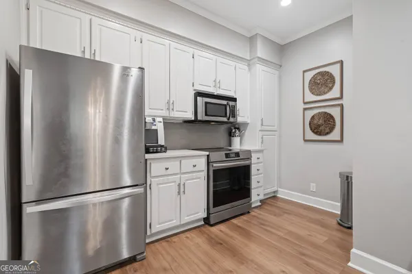 a kitchen with stainless steel appliances a refrigerator a stove and white cabinets