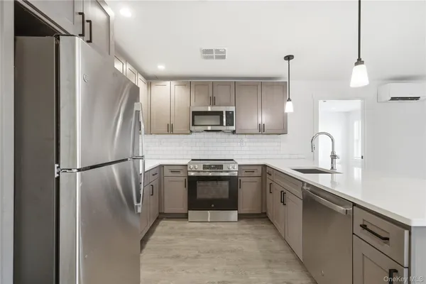 a kitchen with stainless steel appliances granite countertop a refrigerator a sink a stove and a refrigerator with wooden floor