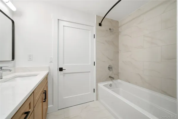 a bathroom with a tub a sink and a mirror