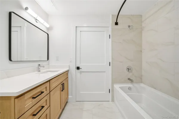 a bathroom with a tub a sink and mirror