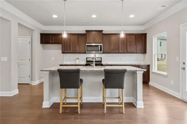 a kitchen with stainless steel appliances granite countertop a stove top oven a sink with white cabinets and wooden floor