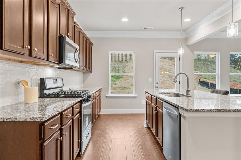 5571 Overview Drive Flowery Branch, GA 30542 - Photo 5 of 38 a kitchen with stainless steel appliances granite countertop a sink stove and cabinets