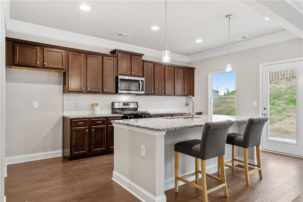 5571 Overview Drive Flowery Branch, GA 30542 - Photo 6 of 38 a kitchen with kitchen island granite countertop wooden floors and stainless steel appliances