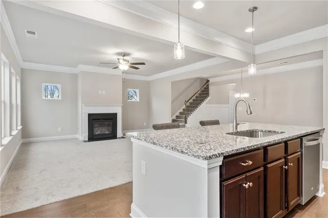 a kitchen with a sink dishwasher a fireplace with wooden floor and chandelier