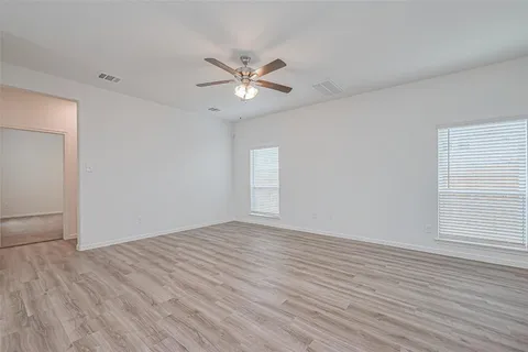 a view of empty room with wooden floor and fan