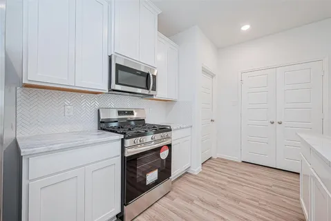 a kitchen with stainless steel appliances white cabinets and a stove top oven
