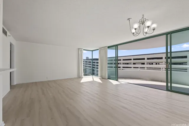 an empty room with wooden floor staircase and a kitchen