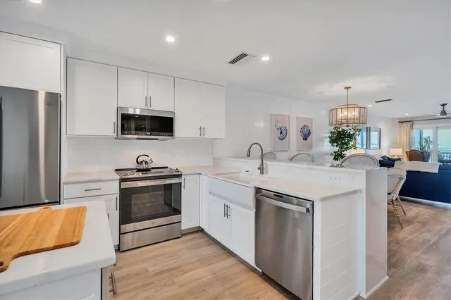 a kitchen with stainless steel appliances a sink a stove a microwave a center island and a refrigerator