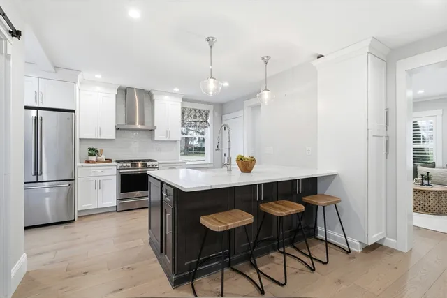 a kitchen with stainless steel appliances a dining table chairs refrigerator and microwave