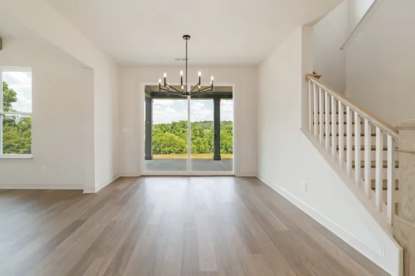 a view of an empty room with wooden floor fridge and a window