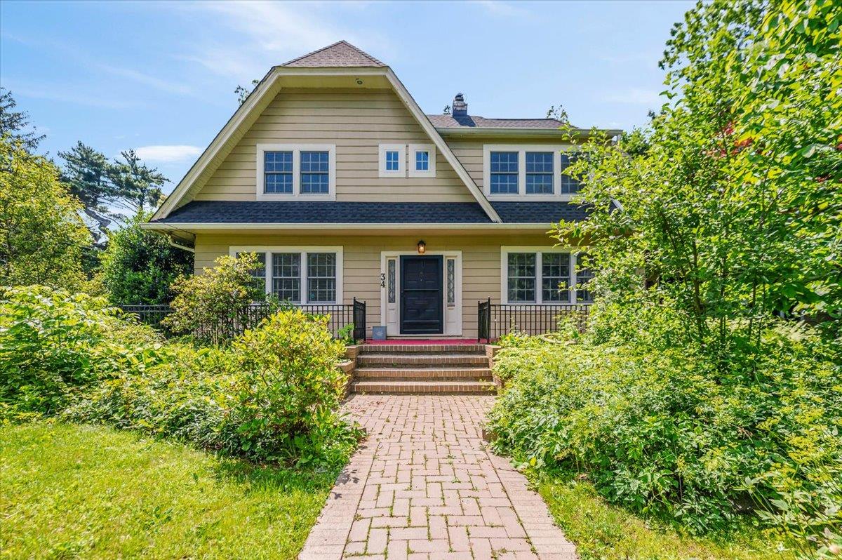 View of front of home with a chimney and roof with shingles