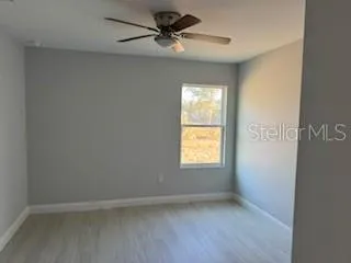 an empty room with a window and a ceiling fan