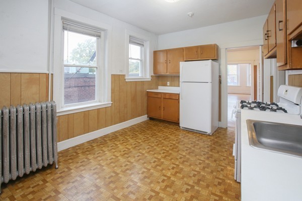 7-9 University Road Brookline, MA 02445 - Photo 15 of 17 a view of a kitchen with a stove top oven a sink dishwasher and a refrigerator with wooden floor