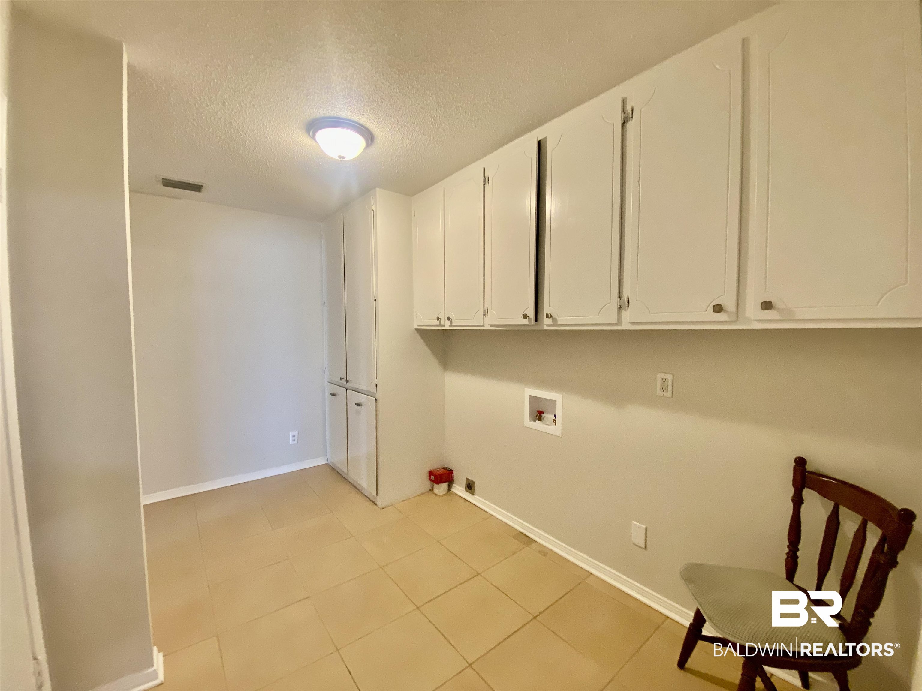 265 Azalea Drive Monroeville, AL 36460 - Photo 18 of 39 Clothes washing area featuring cabinets, washer hookup, a textured ceiling, and light tile patterned flooring