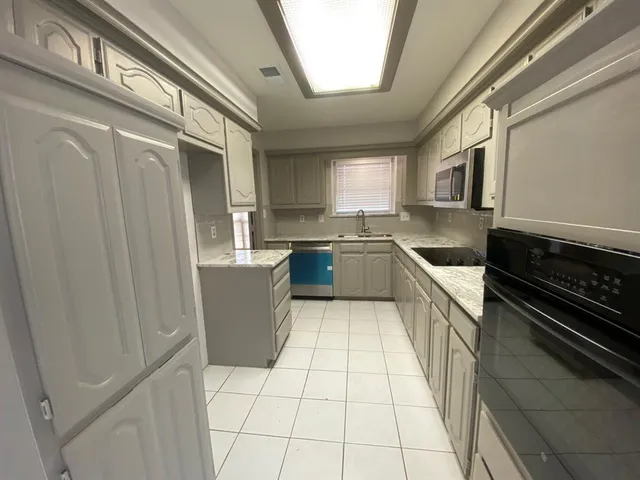 a kitchen with a sink a stove top oven and cabinetry