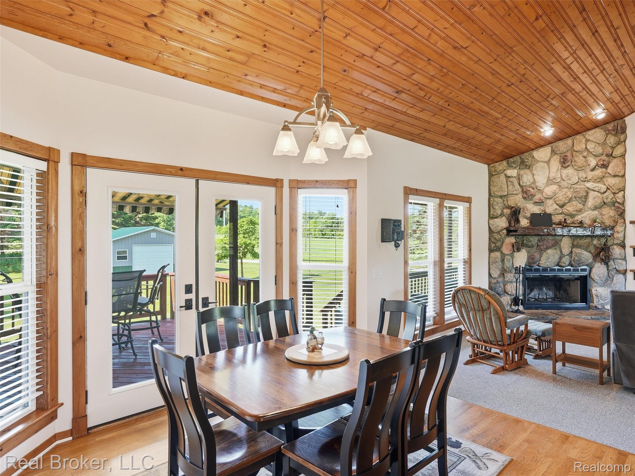 7271 West Ray Road Gaines, MI 48436 - Photo 24 of 48 Spacious dining area featuring wood-finish flooring, a stone accent wall with a fireplace, and a vaulted wood-paneled ceiling