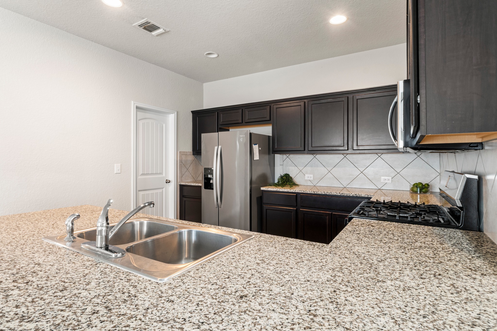 10809 Gonzales Ranger Pass Austin, TX 78754 - Photo 14 of 37 Durable granite countertops pair well with classic tiled backsplash, perfect for easy cleanup.