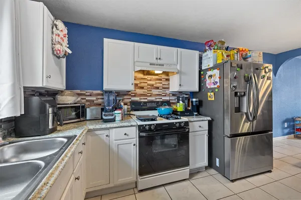 a kitchen with stainless steel appliances granite countertop a refrigerator sink and stove