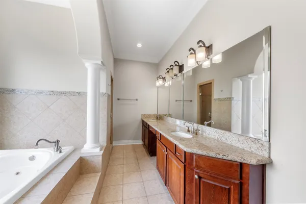 a spacious bathroom with a granite countertop double vanity sink a large mirror and a bathtub