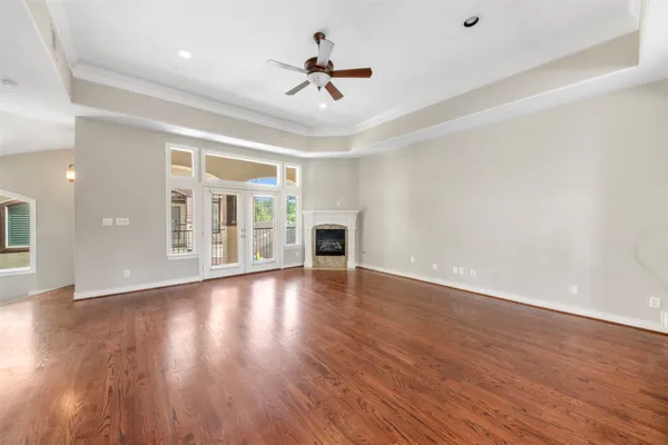 a view of an empty room with wooden floor and a ceiling fan