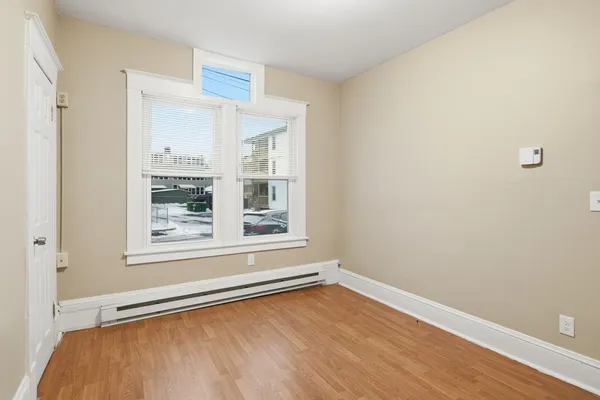 a view of an empty room with wooden floor and closet
