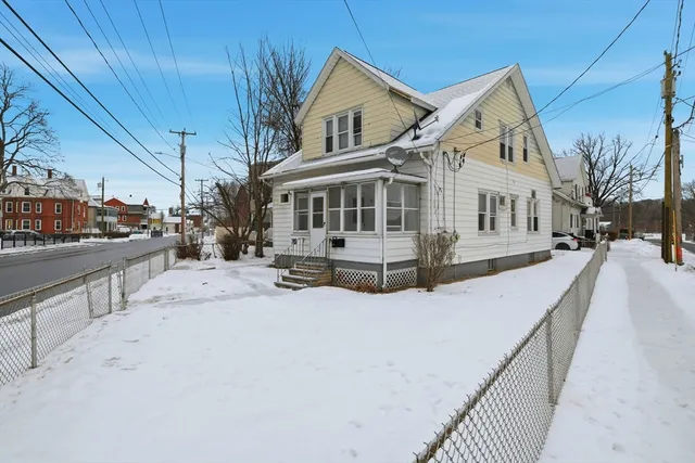 a view of a white house with a yard covered in snow