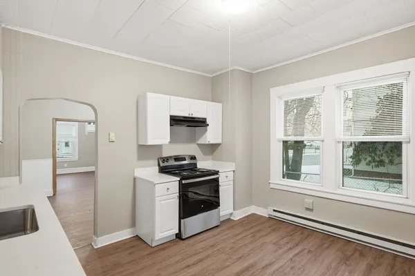 a kitchen with stainless steel appliances wooden floors and white walls