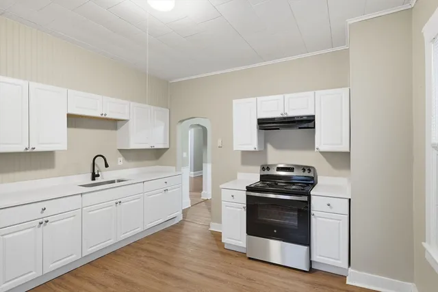 a kitchen with sink a stove and white cabinets