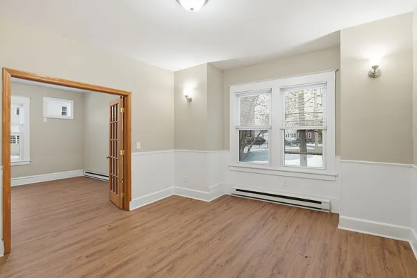 an empty room with wooden floor and windows